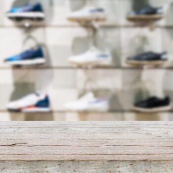 Wood table top with Shoes on shelves in the shoes store blur background, for create product display