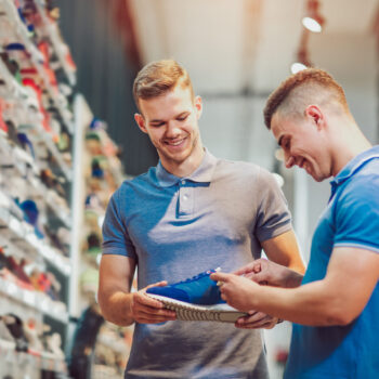 Two man deciding on new sports shoes in sports store