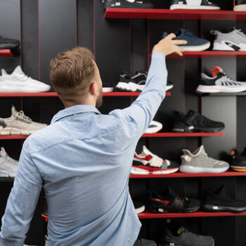 young man picking a sporty shoes in the shop, new sneakers in sports store for men, mens shopping sports shoes